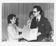 <span itemprop="name">Two unidentified people holding an award presented...</span>