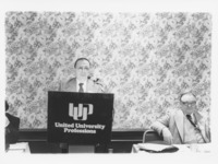 <span itemprop="name">Ernie Fox speaking from a podium during a United...</span>
