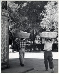 <span itemprop="name">The back of two men walking with large baskets on...</span>