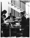 <span itemprop="name">Unidentified students sitting at tables with piles...</span>