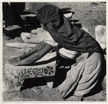 <span itemprop="name">A woman with her shawl wrapped around her head,...</span>