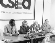 <span itemprop="name">Seated at a table during a press conference are...</span>