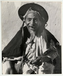 <span itemprop="name">An old man wearing a hat and draped clothing...</span>