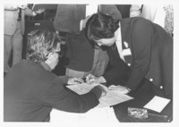 <span itemprop="name">Evelyn Hartman (right) signing a piece of paper...</span>