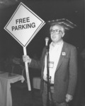 <span itemprop="name">Henry Steck holding a "Free Parking" sign during a...</span>