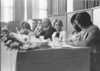 <span itemprop="name">A group of unidentified people seated on the dais...</span>
