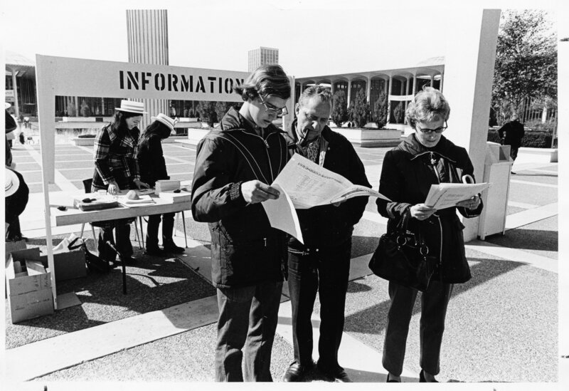 Image of people looking at maps in front of an information boot on the UAlbany campus.